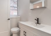 Thumbnail 19 of 35 - A white bathroom with a toilet, sink, and mirror.