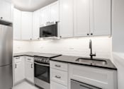 Thumbnail 1 of 35 - A modern kitchen with white cabinets and stainless steel appliances.