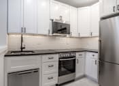 Thumbnail 2 of 35 - A modern kitchen with white cabinets and stainless steel appliances.