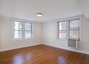 Thumbnail 5 of 35 - A room with wooden floors and two windows.