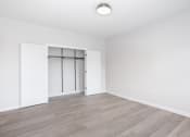 Thumbnail 12 of 22 - an empty living room with white walls and wood flooring and a white closet with