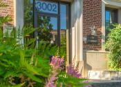 Thumbnail 4 of 22 - the front door of a brick building with flowers in front of it