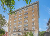 Thumbnail 1 of 21 - a tall brick building with many windows and a street in front