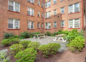 Thumbnail 3 of 16 - the courtyard of a brick building with a picnic table and benches