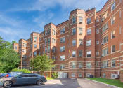 Thumbnail 17 of 35 - a large red brick apartment building with cars parked outside