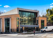 Thumbnail 32 of 41 - a building with large glass windows and a woman crossing the street