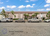 Thumbnail 12 of 17 - A parking lot with several cars and a building in the background with the words Beach Front Property Management.