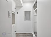Thumbnail 16 of 18 - A white hallway with a door on the left and a window on the right.
