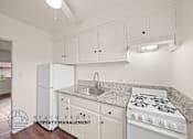 Thumbnail 2 of 17 - A kitchen with white appliances and cabinets.