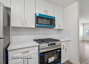 Thumbnail 1 of 21 - A kitchen with white cabinets and a blue microwave.