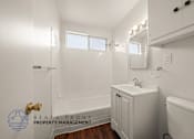 Thumbnail 9 of 17 - A white bathroom with a sink, mirror, and tub.