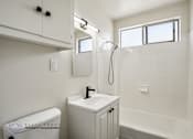 Thumbnail 13 of 18 - A white bathroom with a toilet, sink, and bathtub.