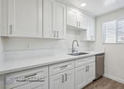 Thumbnail 2 of 21 - A kitchen with white cabinets and a sink.