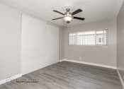 Thumbnail 11 of 13 - A room with a ceiling fan and wooden flooring.