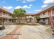 Thumbnail 13 of 17 - A courtyard with a tree in the middle and apartment buildings surrounding it.