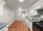 Thumbnail 3 of 32 - A kitchen with wooden floors and white cabinets.