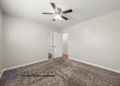 Thumbnail 9 of 32 - A room with a carpet floor and a ceiling fan.
