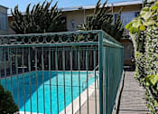 Thumbnail 1 of 10 - a swimming pool is behind a wrought iron fence