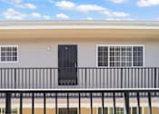 Thumbnail 6 of 14 - A building with a black door and windows with white bars.