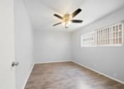 Thumbnail 11 of 14 - A room with a ceiling fan and a window with bars.