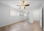 Thumbnail 10 of 14 - A room with a ceiling fan and wooden flooring.