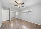 Thumbnail 8 of 14 - A room with a ceiling fan and wooden flooring.