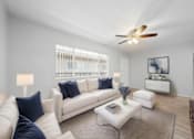 Thumbnail 13 of 14 - A living room with a white couch, a coffee table, and a ceiling fan.