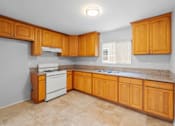 Thumbnail 1 of 14 - A kitchen with wooden cabinets and a white stove top oven.