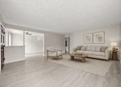 Thumbnail 4 of 6 - A living room with a white couch, a wooden coffee table, and a rug.
