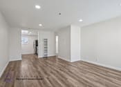 Thumbnail 17 of 21 - A spacious room with wooden flooring and white walls, with a logo for Beach Front Property Management in the bottom left corner.