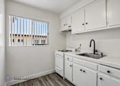 Thumbnail 1 of 18 - A kitchen with white cabinets and a window with blinds.