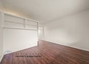 Thumbnail 4 of 17 - A room with wooden floors and white walls, with a logo for Beach Front Property Management in the bottom left corner.