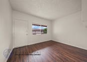 Thumbnail 6 of 17 - A room with wooden floors and a window showing a view of a house.