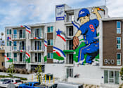 Thumbnail 7 of 33 - A large mural of a baseball player in blue jersey number 9 is painted on the side of a building.