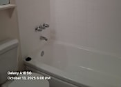 Thumbnail 9 of 10 - A white tiled bathroom with a shower and a toilet.