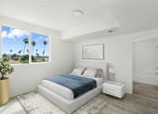 Thumbnail 4 of 33 - A bedroom with a large bed and a view of palm trees outside the window.