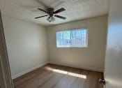 Thumbnail 3 of 6 - A room with a ceiling fan and wooden flooring.