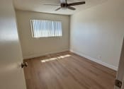 Thumbnail 2 of 6 - A room with a ceiling fan and wooden flooring.