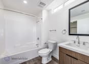 Thumbnail 23 of 33 - A white bathroom with a toilet, sink, and mirror.