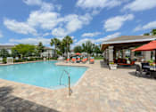 Thumbnail 29 of 40 - A swimming pool surrounded by a brick patio and lounge chairs.