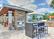 Thumbnail 30 of 40 - A patio with a bar and stools.