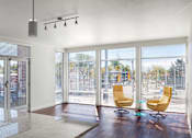 Thumbnail 10 of 16 - a living room with sliding glass doors and a kitchen with a sink and chairs