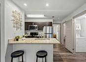 Thumbnail 9 of 36 - A kitchen with a granite countertop and a bar stool.
