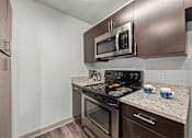 Thumbnail 11 of 36 - A modern kitchen with a stainless steel oven and microwave.