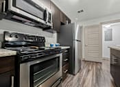 Thumbnail 12 of 36 - A modern kitchen with a stainless steel refrigerator and oven.