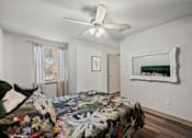 Thumbnail 15 of 36 - A bedroom with a floral bedspread and a white ceiling fan.