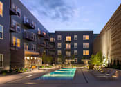 Thumbnail 15 of 16 - a pool is lit up in the middle of an apartment complex at night