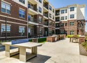 Thumbnail 9 of 23 - an outdoor patio with a picnic table in front of an apartment building