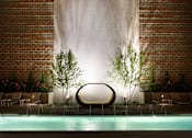 Thumbnail 14 of 16 - a pool with a chair in front of a brick wall