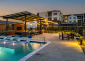 Thumbnail 5 of 23 - a swimming pool with lounge chairs and umbrellas at dusk